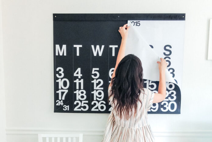 A conceptual image of a woman turning a calendar to a new month.