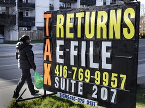 A person walks past tax help advertising on Toronto’s Jane Street prior to the income tax filing deadline on April 25.
